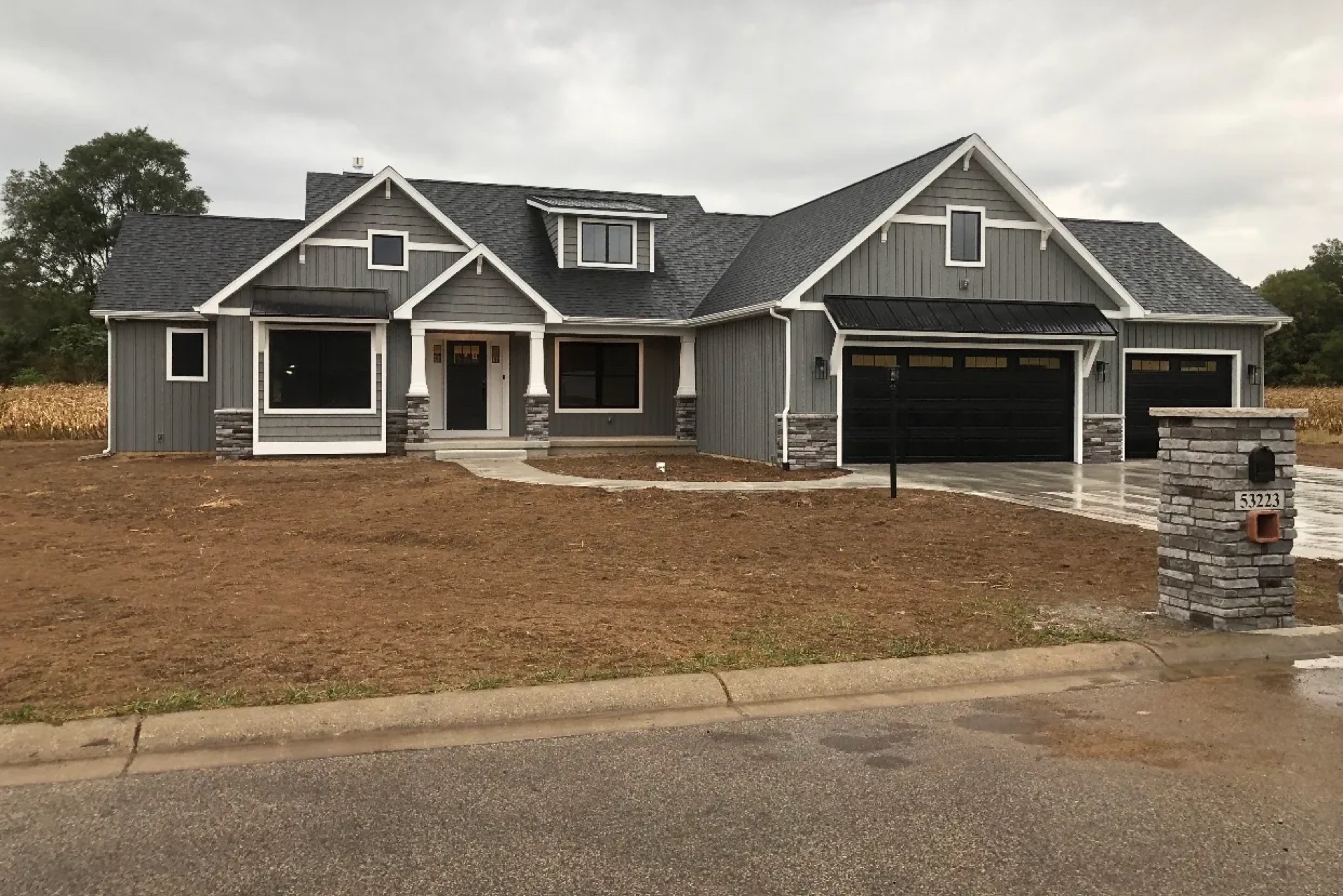 Custom craftsman two-story home with dark garage doors and stone accents