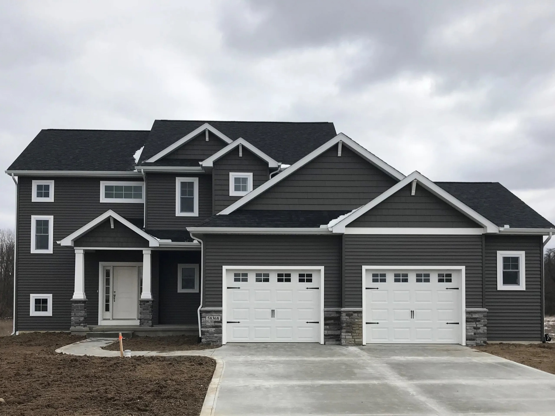 Two-story custom home with dark charcoal siding and white garage doors