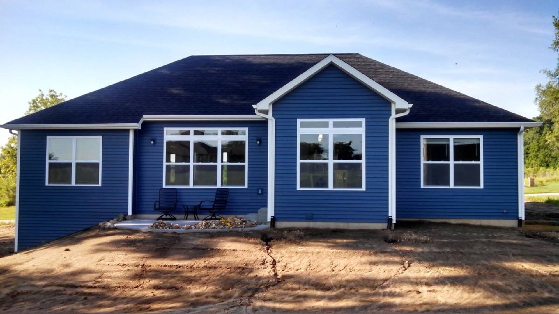 Custom ranch home rear exterior with bold blue siding and large windows