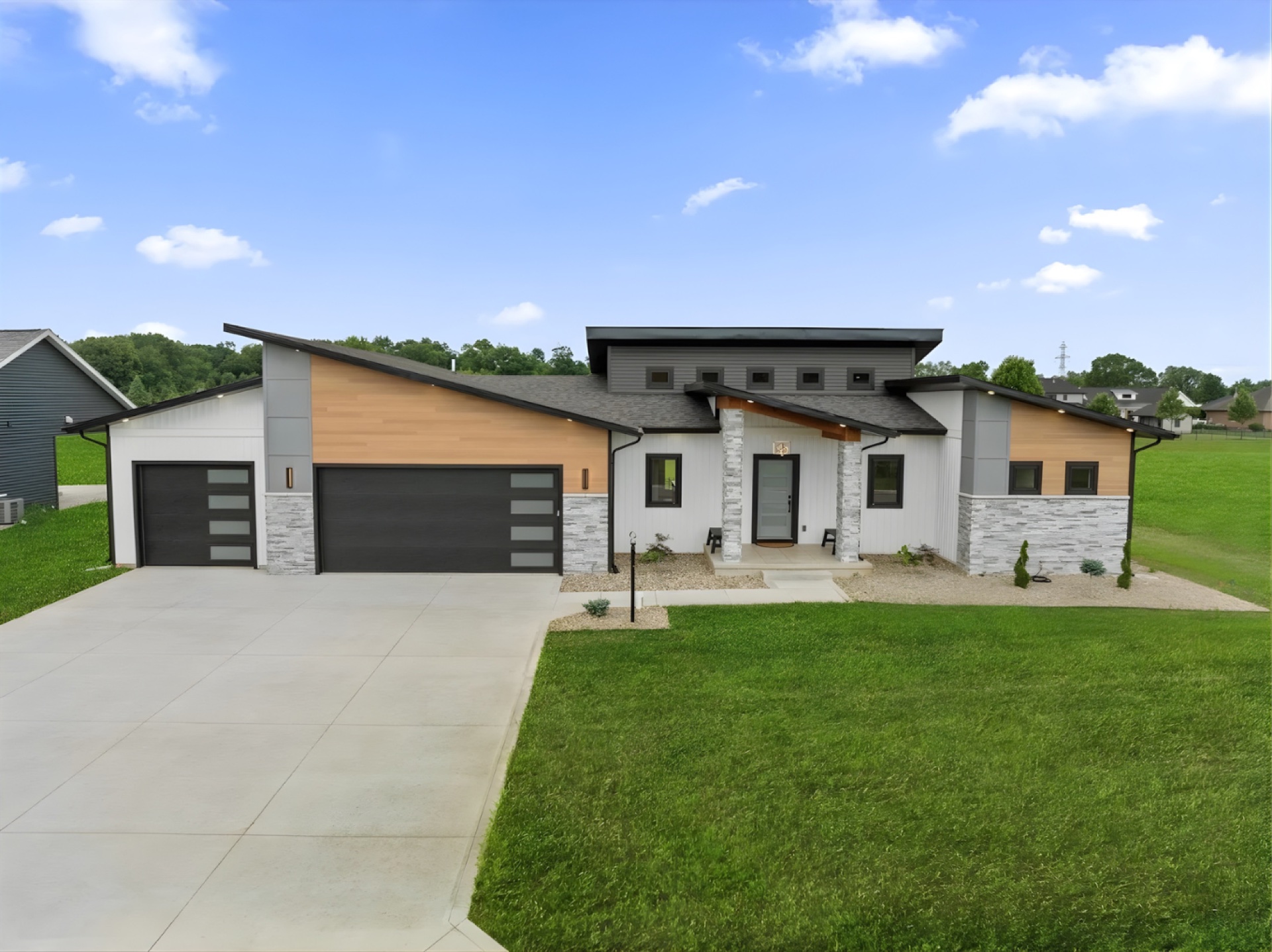 Modern contemporary custom home with wood accents, stone, and dark garage doors