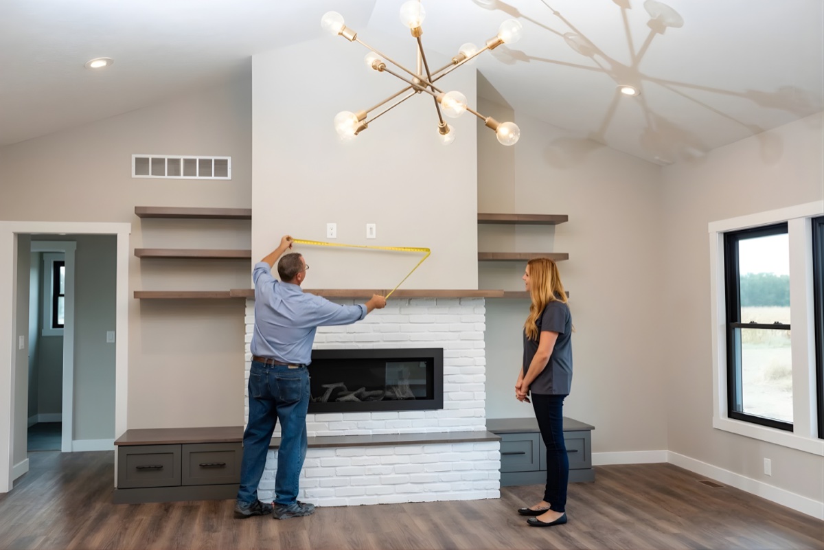 Custom living room with white brick fireplace, sputnik chandelier, and wood shelving