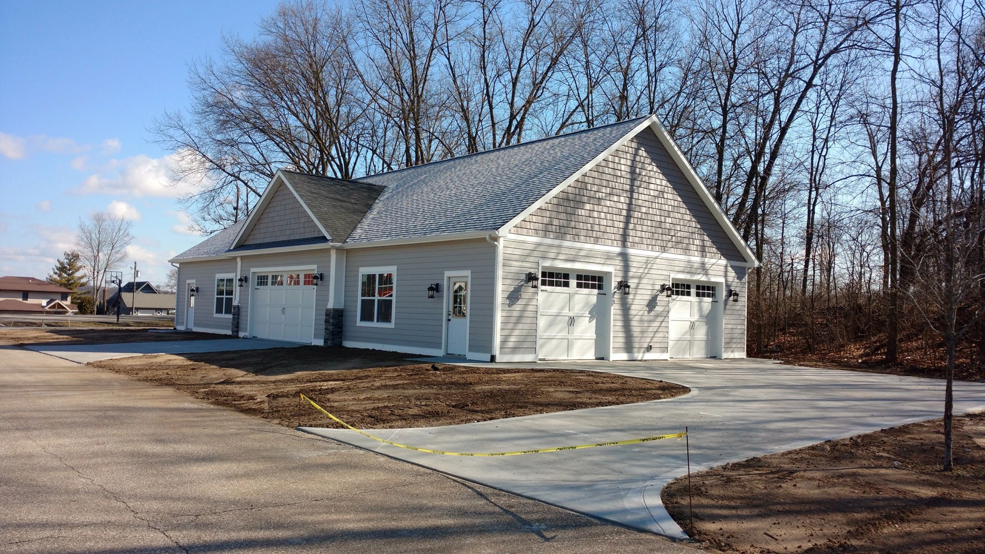 Custom craftsman toy barn exterior with attached garage and fresh concrete driveway