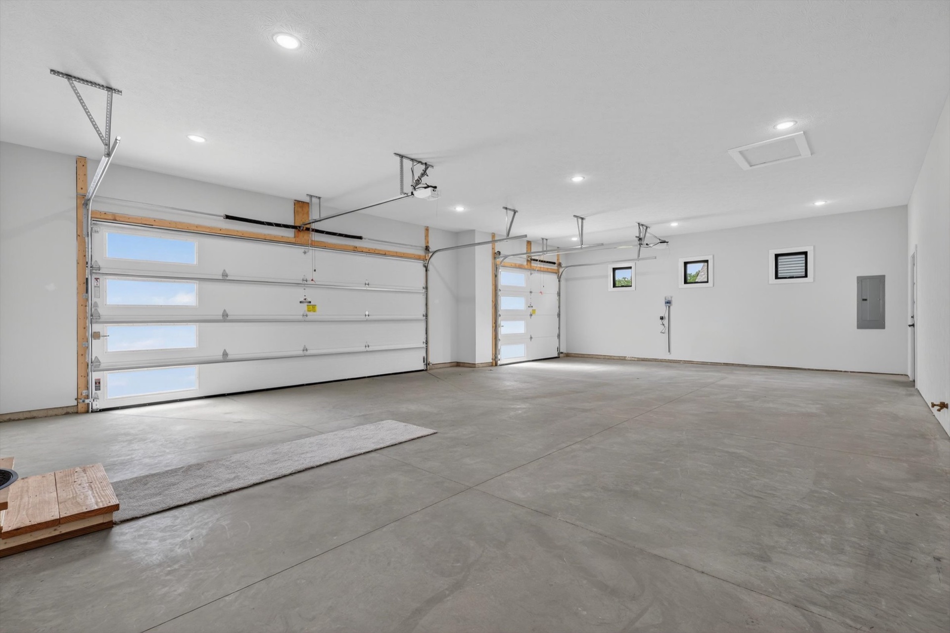 Spacious three-car garage interior with modern horizontal window overhead doors and polished concrete floor