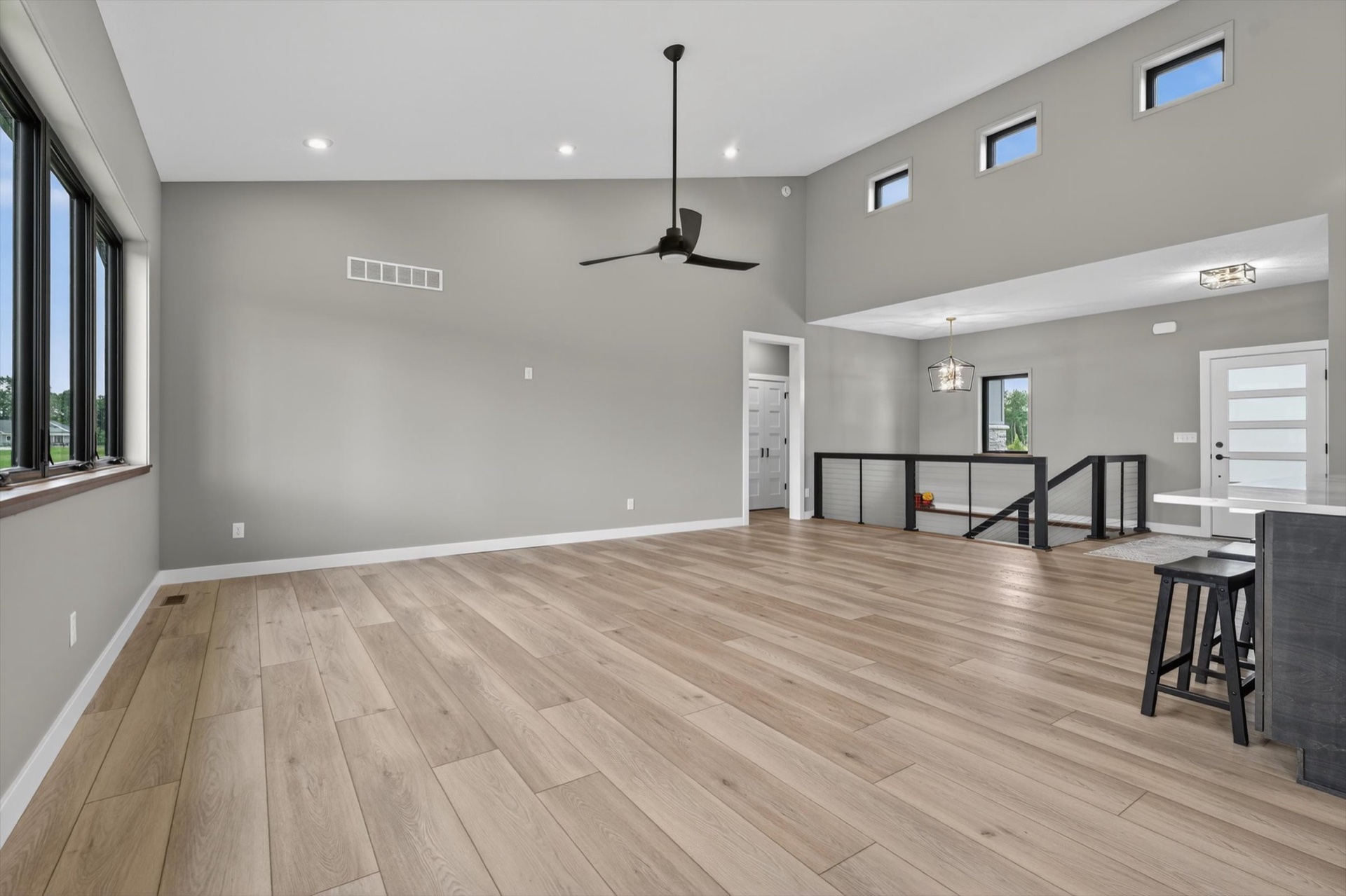 Open concept great room with vaulted ceiling, ceiling fan, and light hardwood floors