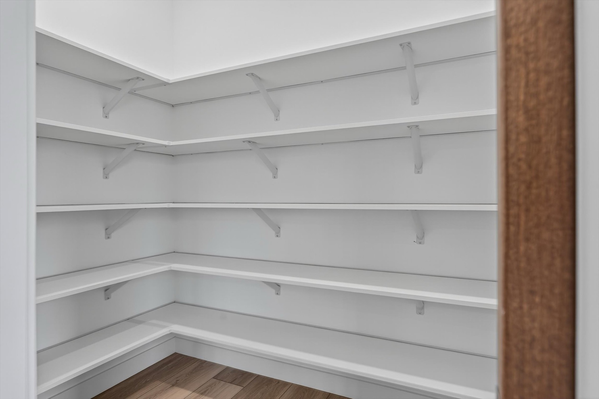 Custom walk-in pantry with white shelving and hardwood floors