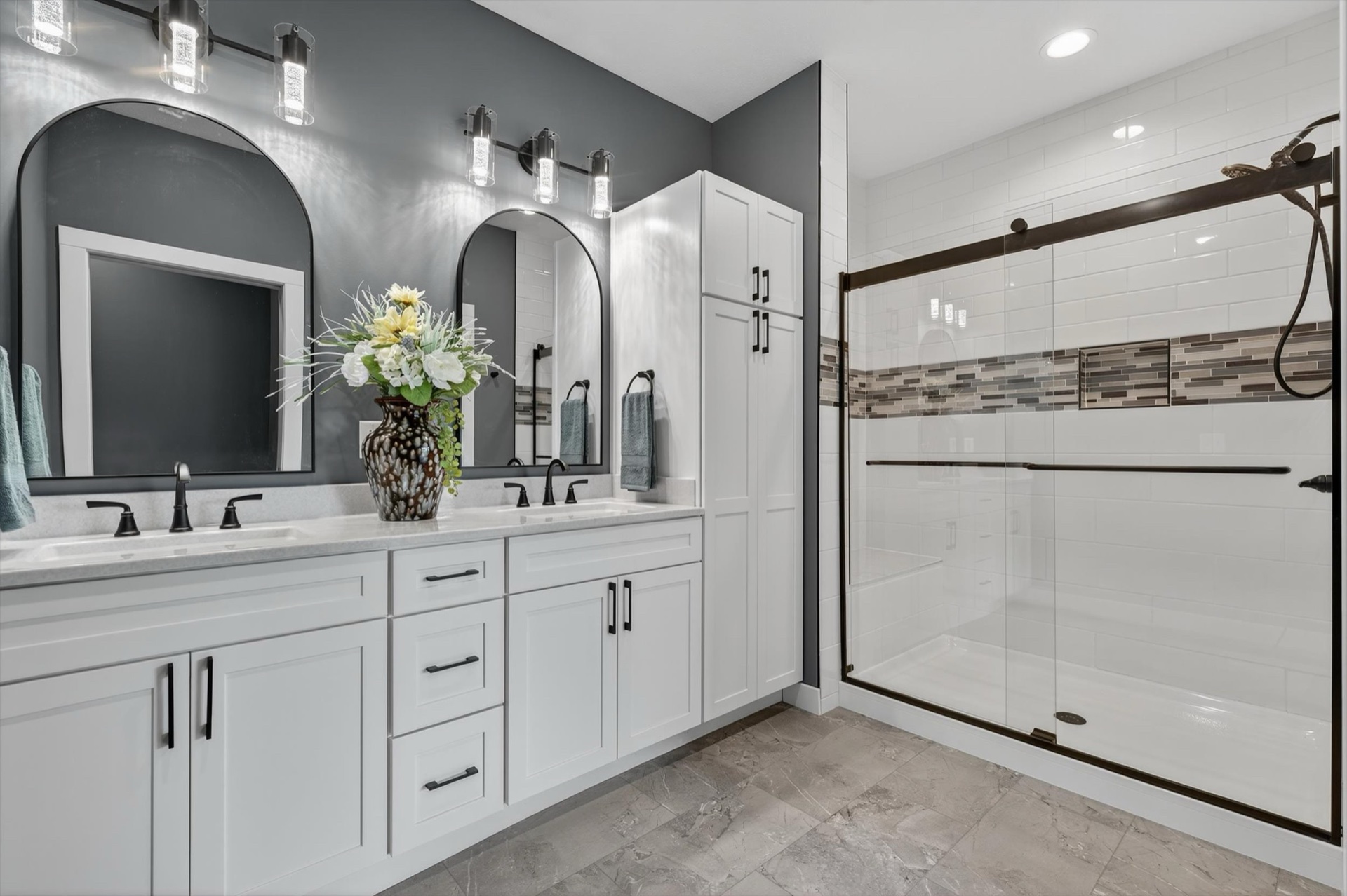Custom master bathroom with double vanity, arched mirrors, and walk-in glass shower