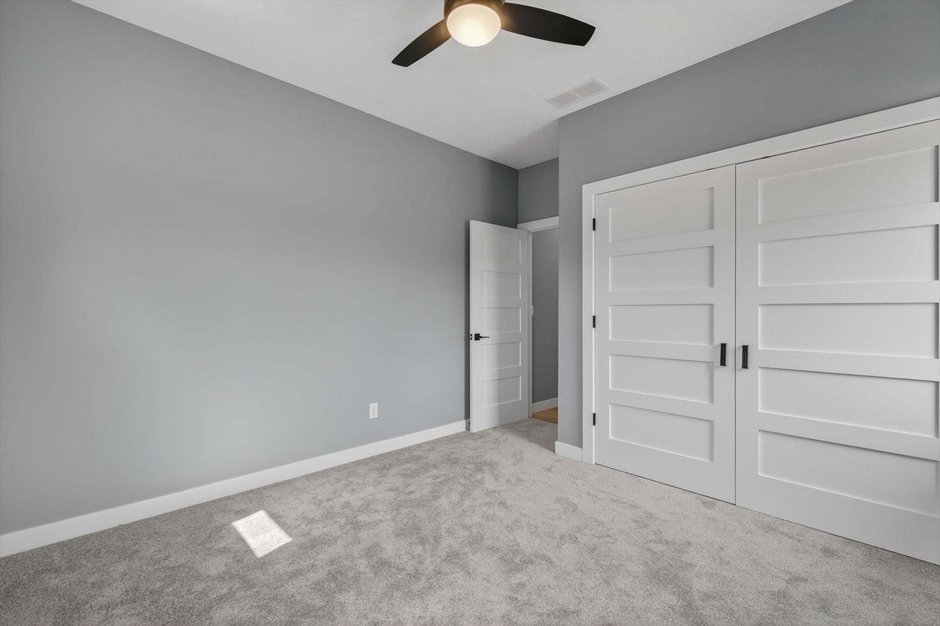 Custom bedroom with ceiling fan, carpet, and double closet doors