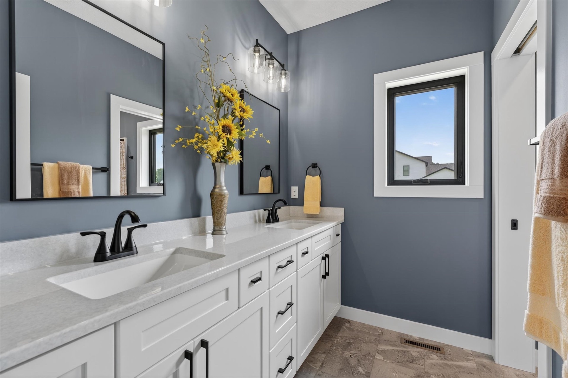 Custom bathroom with double vanity, blue accent walls, and matte black fixtures