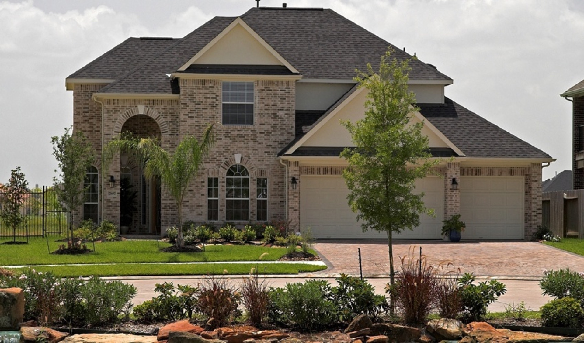 Two-story custom home with brick facade, arched windows, and three-car garage