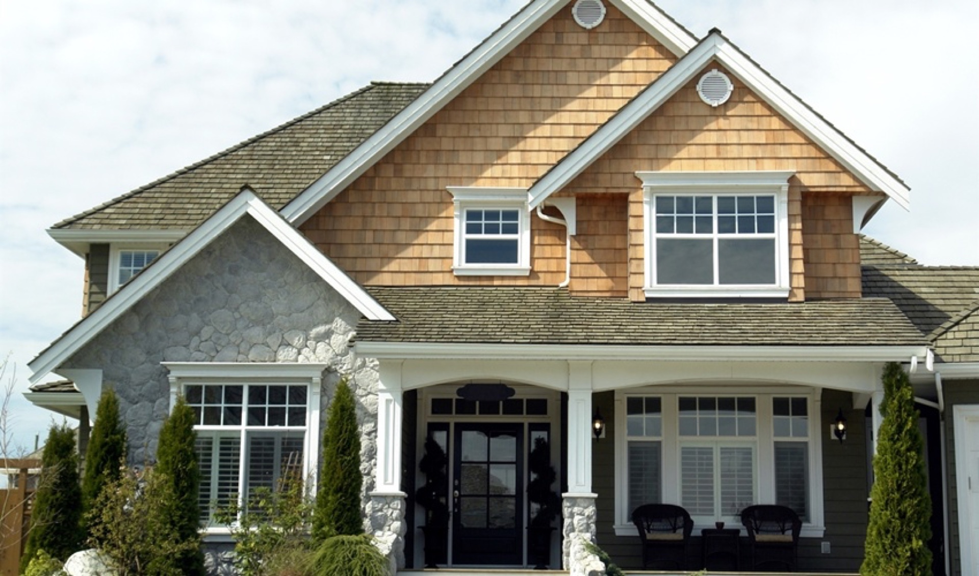 Two-story craftsman custom home with cedar shake, stone columns, and black front door