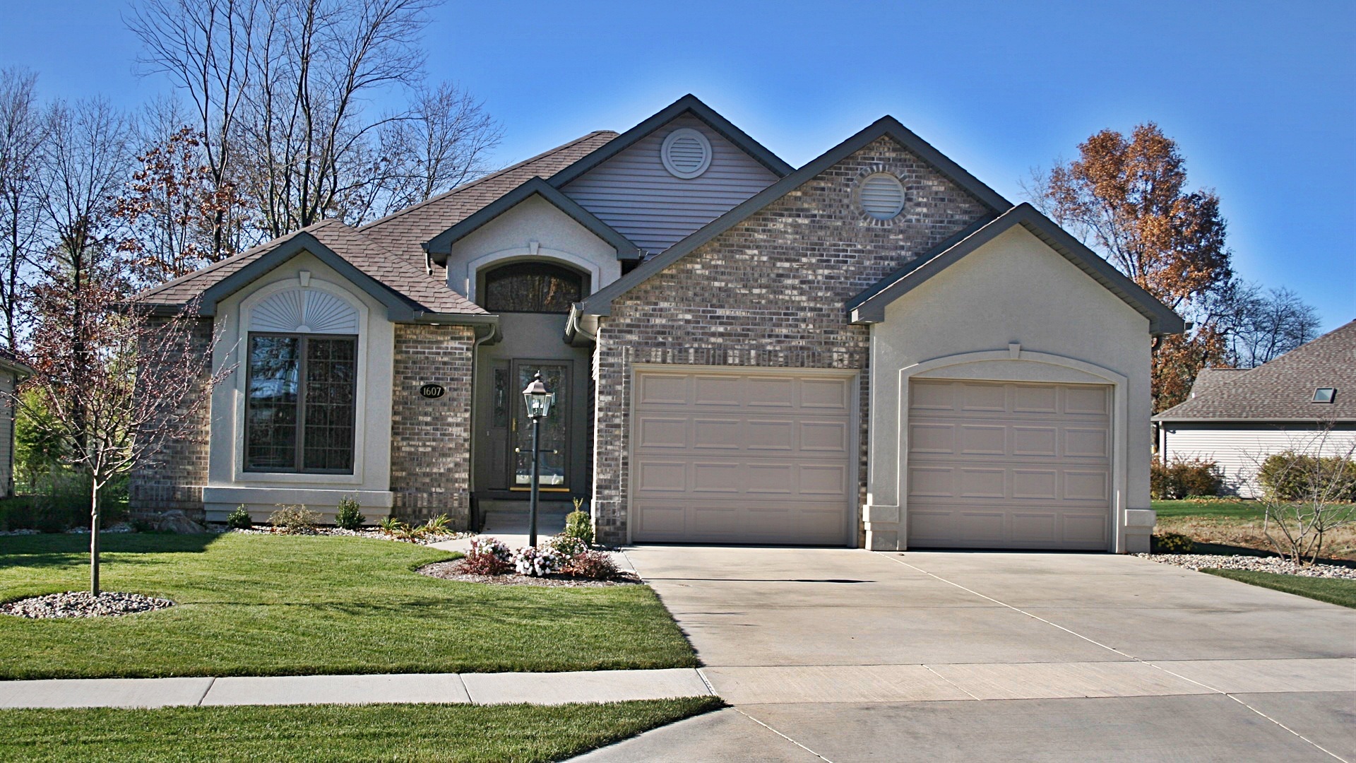 Custom ranch home with brick and stucco exterior, arched entry, and two-car garage