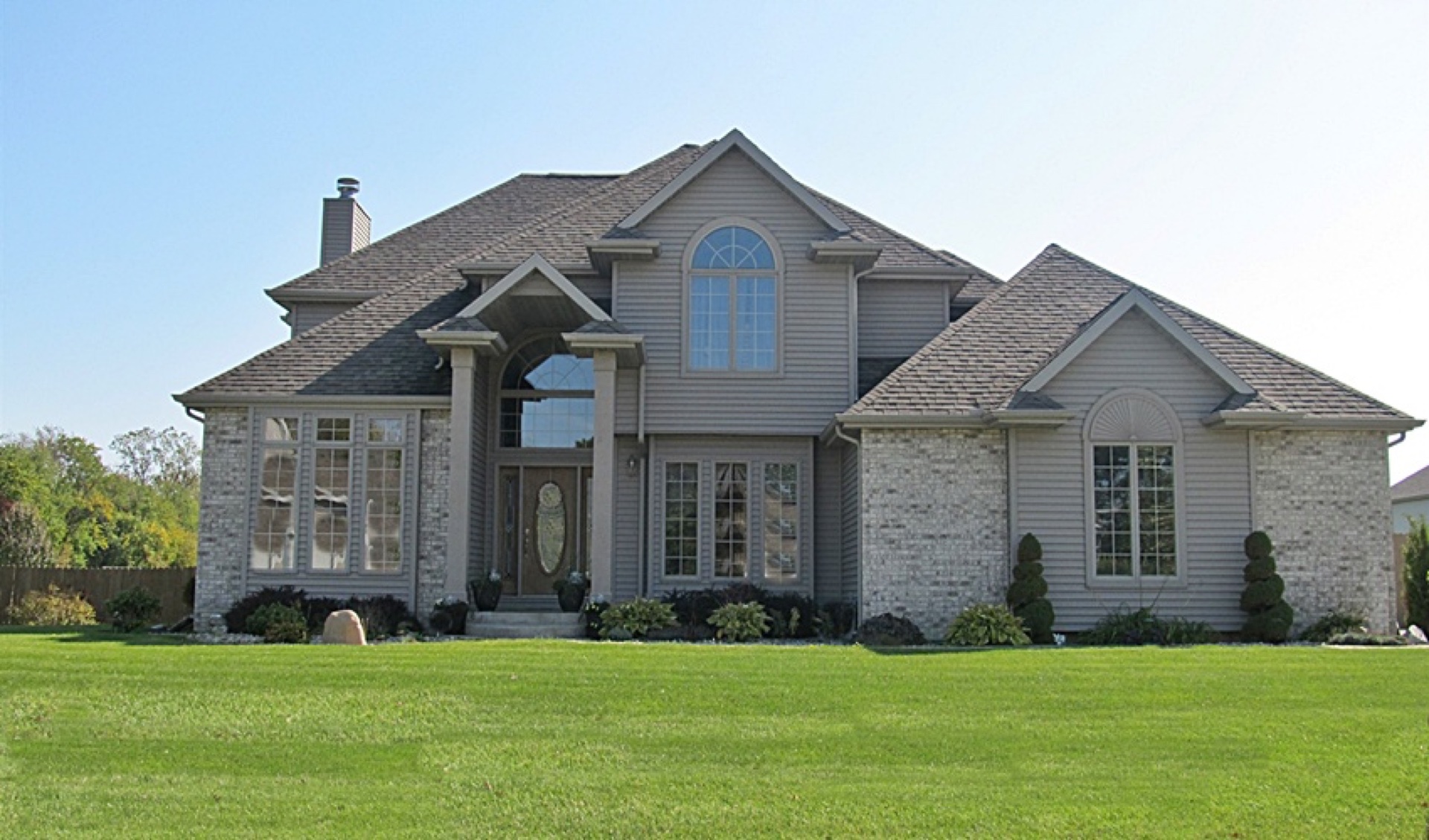 Two-story custom home with brick exterior, arched windows, and columned entry